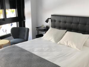 a bedroom with a bed and a chair and a window at Apartamentos Kronox in Nerja