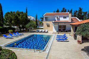 a villa with a swimming pool and chairs and a house at 6 bdr villa with TENNIS COURT in Paphos City