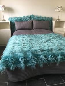 a bed with a blue furry blanket on it at Lolland Bed & Breakfast in Søllested