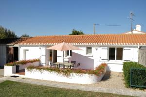 a white house with a table and an umbrella at Maison de campagne pour 6 in Commequiers