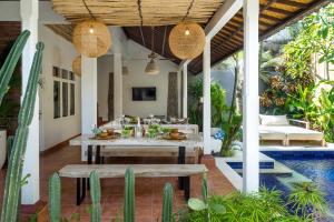 an outdoor dining area with a table and benches at Smiling Cactus Villas - Seminyak in Seminyak