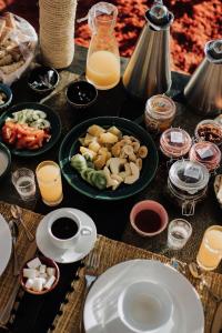 a table topped with plates of food and orange juice at Desert Luxury Camp Erg Chigaga in El Gouera