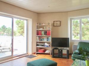 a living room with a tv and a book shelf at Maison pour 6 - jardin et terrasse - 300m plage in Brétignolles-sur-Mer