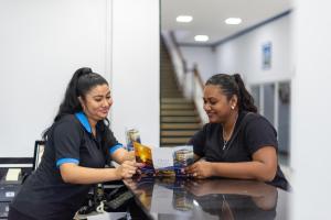 two women sitting at a table looking at a book at Status International Hotel in Georgetown