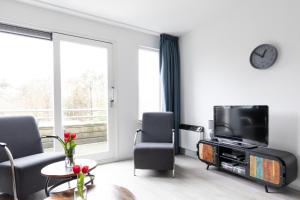 uma sala de estar com uma televisão e uma mesa e cadeiras em Amelander Kaap 126 em Hollum