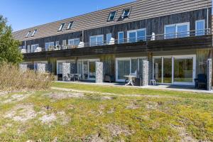 a large building with a balcony and a yard at Amelander Kaap 126 in Hollum