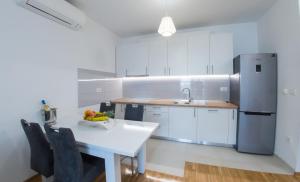 uma cozinha branca com uma mesa e um frigorífico em Apartment Oasis em Mostar