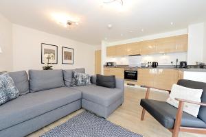 a living room with a couch and a kitchen at Woking Town Centre - Parking Included by Deilamy Homes in Woking