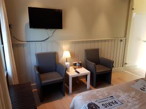 una camera con due sedie, un tavolo e una TV di B & B DE SERAFIJN a Lochristi