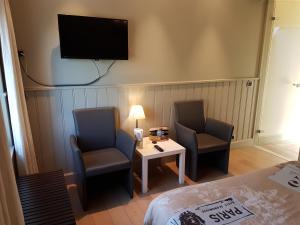 een kamer met 2 stoelen, een tafel en een tv bij B & B DE SERAFIJN in Lochristi