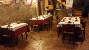 una fila de mesas en un restaurante con manteles rojos y blancos en La via del parco en Arsita