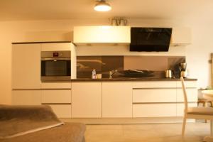 a kitchen with white cabinets and a microwave at FEWO 1 in Wiek auf Rügen
