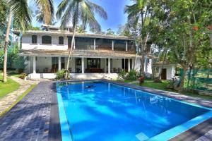 an exterior view of a house with a large blue swimming pool at Amara Villa in Galle