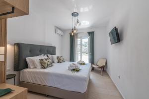sypialnia z łóżkiem z białą pościelą i oknem w obiekcie Flora's Houses Mykonos w mieście Klouvas