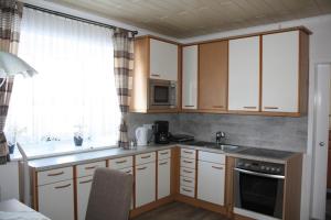 kuchnia z białymi szafkami, zlewem i oknem w obiekcie Ferienapartment Ulrike w mieście Engelstein