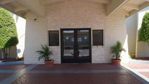 einer Eingangstür eines Gebäudes mit zwei Topfpflanzen in der Unterkunft Travelodge by Wyndham North Richland Hills/Dallas/Ft Worth in North Richland Hills