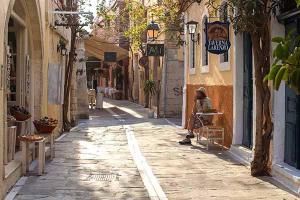 una persona sentada en un banco en un callejón en Angel's house en Rethymno