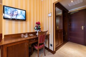een kamer met een bureau en een televisie aan de muur bij Hotel Lido - Beach and Palace in Bolsena