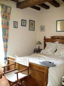 a bedroom with a wooden bed and a chair at La Mesnagerie in Jarzé