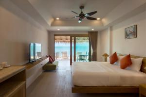 1 dormitorio con cama, TV y balcón en Lipa Lodge Beach Resort, en Lipa Noi