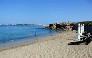 a beach with umbrellas and people in the water at Amphora Hotel & Suites in Paphos