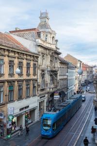 een blauwe trein in een stadsstraat met gebouwen bij Pierrot & Pierrette in Zagreb