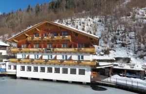 a large wooden building with a balcony on the water at Hotel-Garni Seestrand in Zell am See