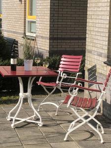 uma mesa vermelha e branca e uma cadeira sentada ao lado de uma mesa em Perle am Ijsselmeer mit eigenem Tretboot em Medemblik