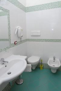 bagno bianco con lavandino e servizi igienici di Villaggio Lido Del Mare a Rodi Garganico