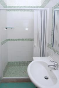 bagno bianco con lavandino e doccia di Villaggio Lido Del Mare a Rodi Garganico