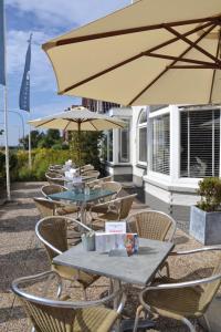 een groep tafels en stoelen met parasols bij Hotel Koogerend in Den Burg