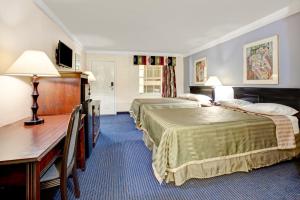 a hotel room with two beds and a desk at Travelodge by Wyndham North Richland Hills/Dallas/Ft Worth in North Richland Hills