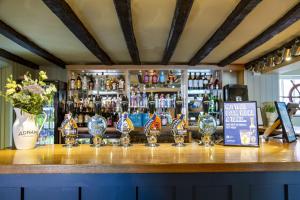 a bar with several wine glasses on a counter at The Cross Keys, Aldeburgh in Aldeburgh