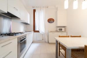 une cuisine avec des placards blancs et une table dans l'établissement San MArtino Apartment, à Venise