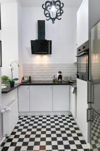a kitchen with white cabinets and a checkered floor at Stara Praga Vistula Apartment in Warsaw