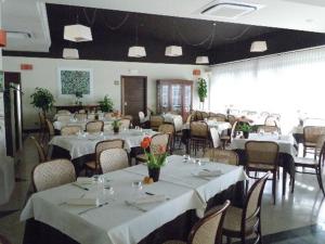 una sala da pranzo con tavoli e sedie con lenzuola bianche di Hotel Adriatico a Tricase