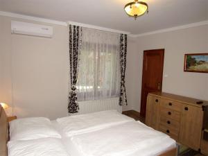 Szegfű Apartman في هایدوسوبوسلو: غرفة نوم بسرير ابيض ونافذة