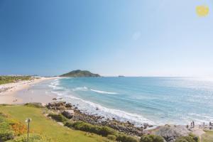 uma vista para uma praia com pessoas andando na areia em Costao do Santinho Resort All Inclusive em Florianópolis
