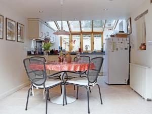 a kitchen with a table with chairs and a refrigerator at Maisey Cottage in Lechlade