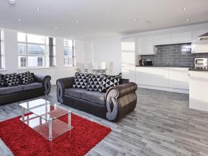 a living room with two couches and a red rug at Fabrik: Winter Gardens Service Apartments 2 in Blackpool
