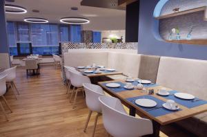 a dining room with wooden tables and white chairs at Hotel Peterhof - urban lifestyle Kempten in Kempten
