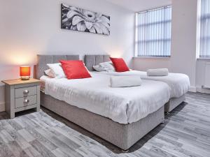 two beds with red pillows in a bedroom at Fabrik: Winter Gardens Service Apartments 2 in Blackpool