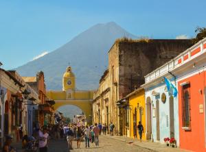 a group of people walking down a street with a clock tower at Ave del Paraiso Guest House in Antigua Guatemala