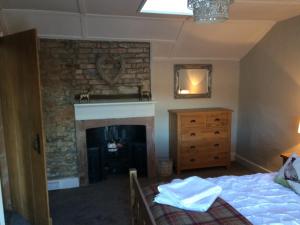 1 dormitorio con 1 cama y chimenea en 'Stokoe Cottage' en Alston