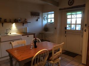 una cocina con una mesa de madera con sillas y una puerta en 'Stokoe Cottage' en Alston