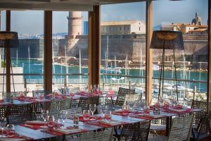 a dining room with tables and chairs and a view of the harbor at Novotel Marseille Vieux Port in Marseille