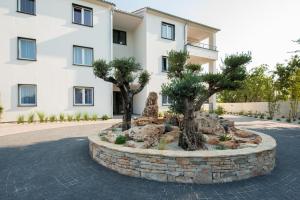 two trees in a stone circle in front of a building at Villa Anja 2nd floor in Peroj