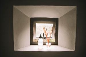 a shelf with a window with a bottle and chopsticks at St Francis Cottage close to beach in St Francis Bay