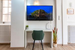 una TV su un muro sopra una scrivania con sedia di Arles Holiday - La Terrasse a Arles