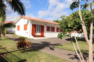 uma casa branca e vermelha com palmeiras em Gite les Bananiers em Saint-Joseph